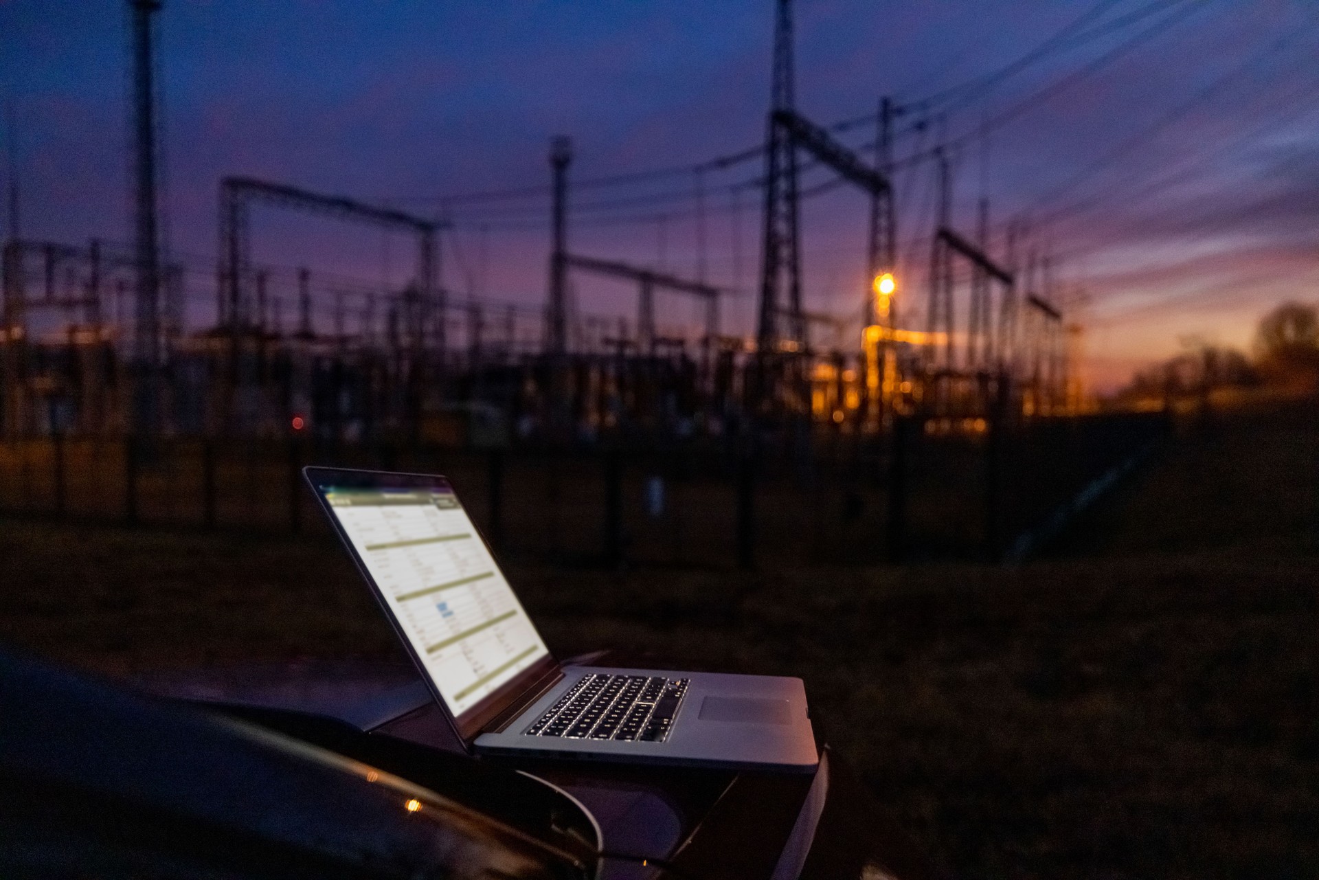 Working laptop and High voltage towers in the dusk of the evening at the back